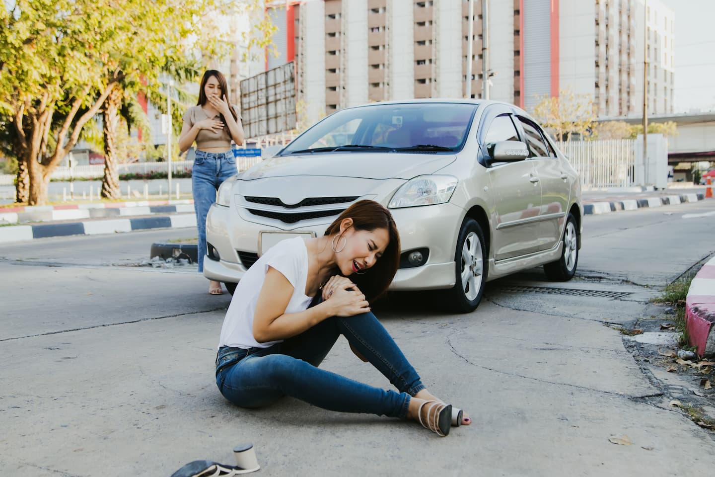 shocked woman watching woman being hit by car while crossing road sitting floor injured 1